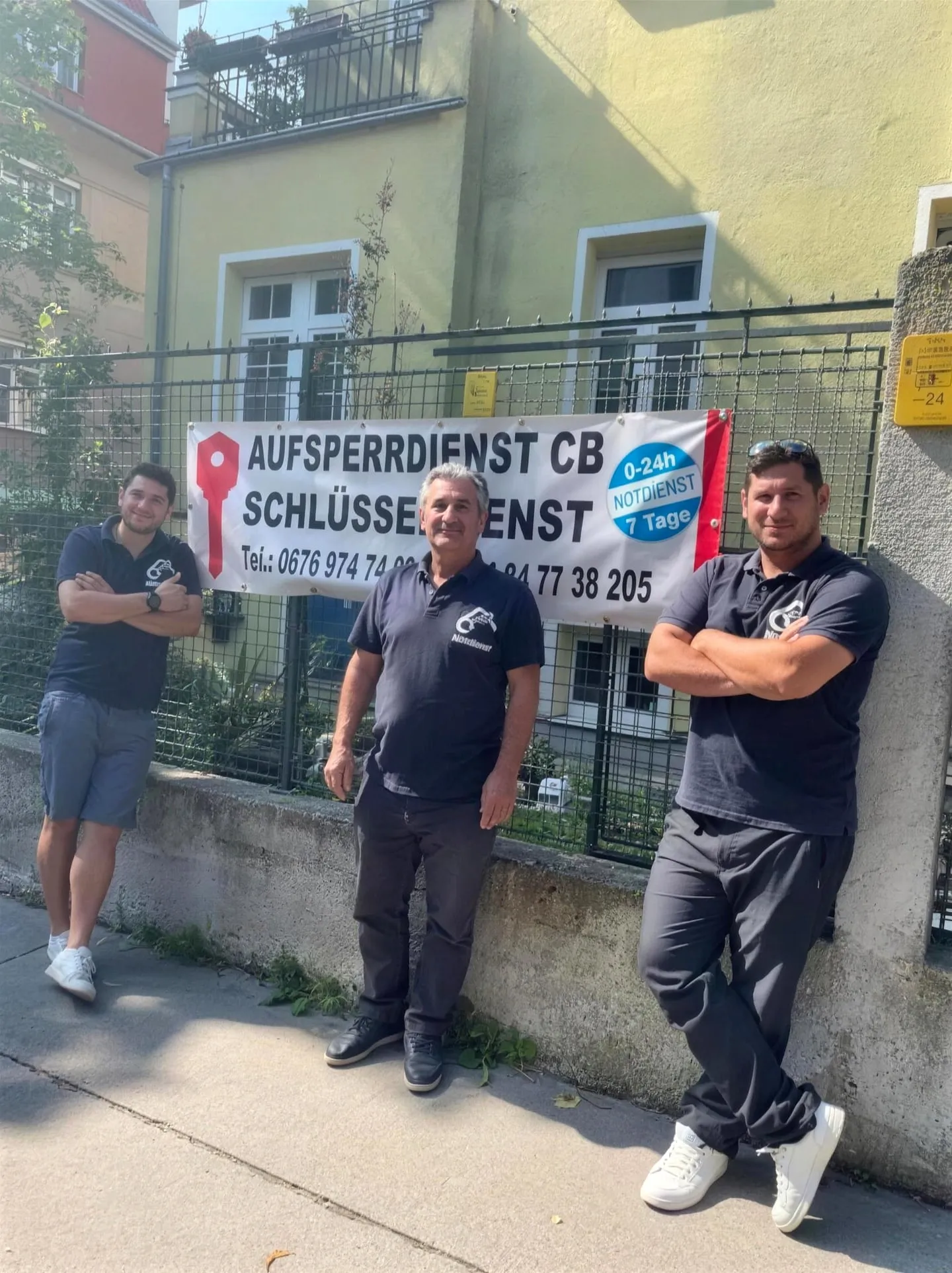 Vater und zwei Söhne im Firmen-Poloshirt vor dem Banner von Aufsperrdienst CB in Wien.