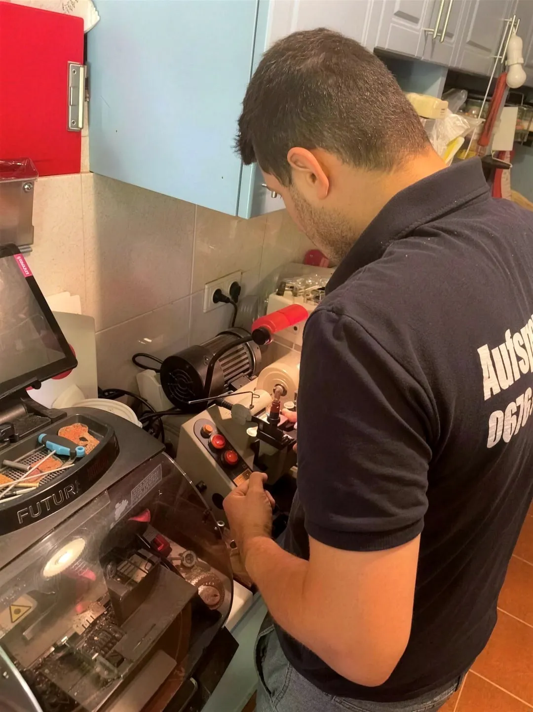 Ein Sohn fertigt an der Schlüsselmaschine in der Werkstatt einen Nachschlüssel.